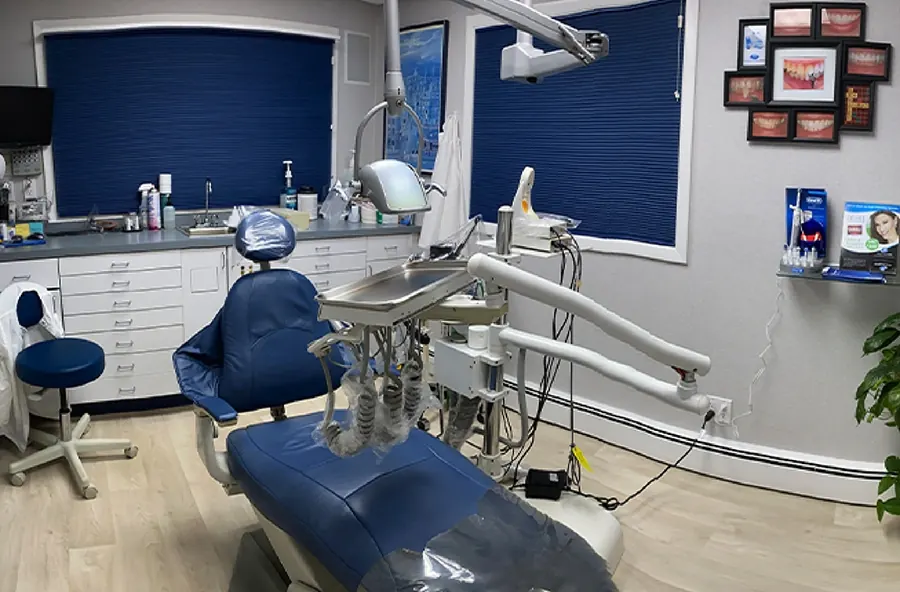 A treatment room with a navy dental chair and smile photographs on the wall.