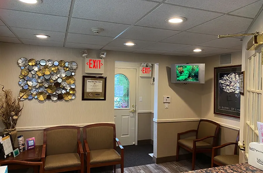 The waiting room, with wooden armchairs and a metallic wall sculpture.