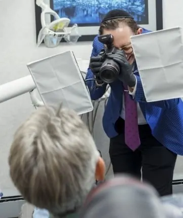 Dr. Ariel photographing a patient's smile with a professional camera and light panels.