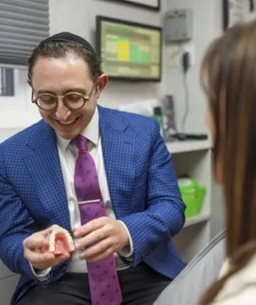 Dr. Ariel holding a dental model while talking a patient through her design.